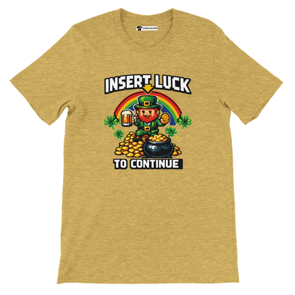 Pixel art leprechaun with beer, gold coins, rainbow, and shamrocks on yellow tee. 'Insert Luck To Continue' text. St. Patrick's Day gamer shirt.
