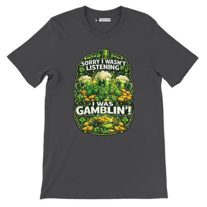 Dark gray graphic tee with shamrocks, gold coins, beer mugs, and 'Sorry I Wasn't Listening I Was Gamblin'' text.
