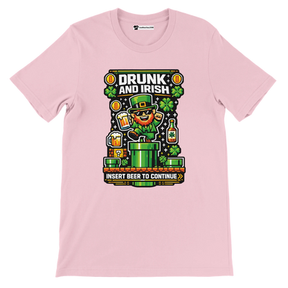 Pink 'Drunk and Irish' pixel art tee with leprechaun, beer, shamrocks, and 'Insert Beer to Continue' gaming text for St. Patrick's Day.