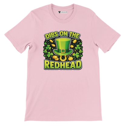 Pink t-shirt with St. Patrick's Day design, green leprechaun hat, shamrocks, gold coins, and 'Dibs on the Redhead' quote.