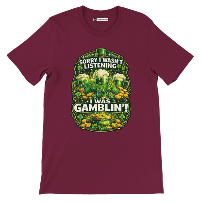 Burgundy t-shirt with St. Patrick's Day theme, beer mugs, game controllers, coins, and 'Sorry I wasn’t listening I was gamblin’' quote.