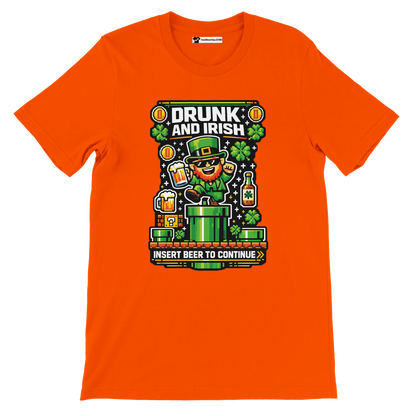 Orange 'Drunk and Irish' tee with pixel leprechaun, beer mugs, shamrocks, and 'Insert Beer to Continue' text for St. Patrick's Day.