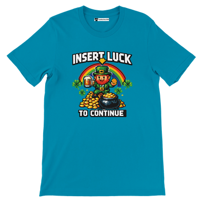 Blue t-shirt with pixel art leprechaun, rainbow, gold coins, shamrocks, and 'Insert Luck To Continue' text for St. Patrick's Day.