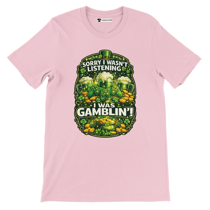 Pink tee with shamrocks, gold coins, green beer, and 'Sorry I wasn't listening, I was gamblin'' quote.