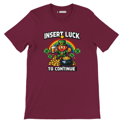 Pixel art leprechaun with rainbow, gold coins, and beer on maroon tee, 'Insert Luck to Continue'