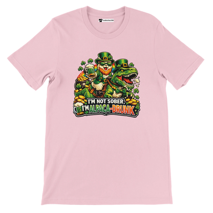 Pink St. Patrick's Day tee with leprechaun riding dinosaur, shamrocks, gold coins, and 'I'm Alpaca-Drunk' text