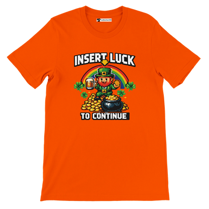 Orange pixel art St. Patrick's Day tee with leprechaun, rainbow, shamrocks, and 'Insert Luck To Continue' text